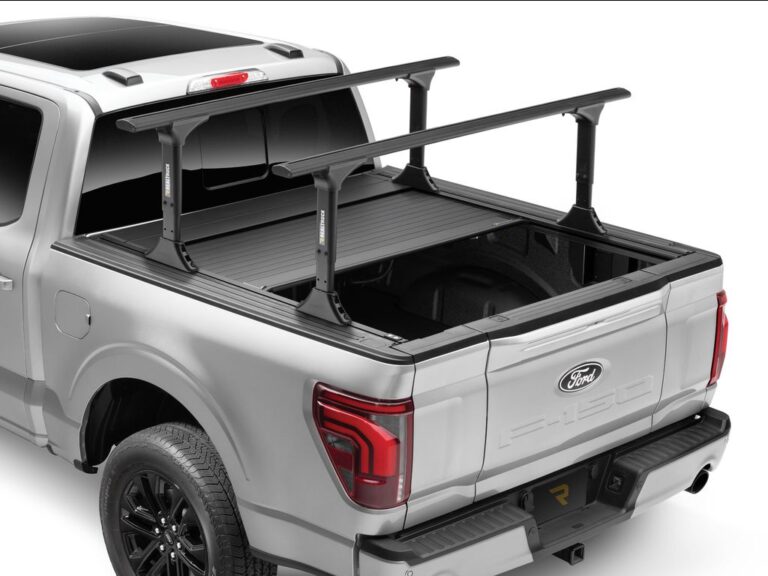 RealTruck FlushFit TS electric retractable cover partially open on a silver Ford F-150 with T-slot rack system mounted on top, rear three-quarter angle on white background