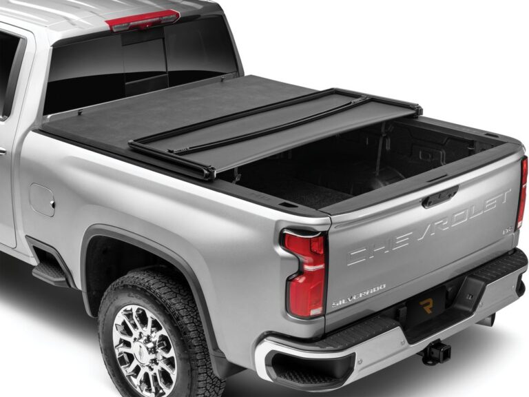 Silver Chevrolet Silverado 2500HD with the Extang Trifecta E-Series soft folding tonneau cover partially open, rear panel lifted forward to expose the bed, rear three-quarter angle on a white background.