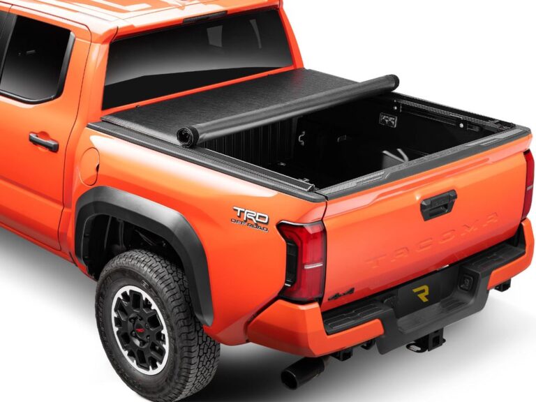 RealTruck TruXedo Lo Pro soft roll-up tonneau cover partially open on an orange Toyota Tacoma TRD Off-Road 4x4, rear three-quarter view on white background