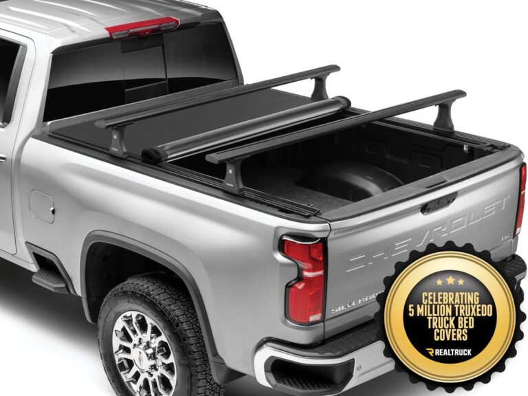 RealTruck TruXedo Pro X15 TS soft roll-up tonneau cover with T-slot crossbars mounted on a silver Chevrolet Silverado, demonstrating rack compatibility, rear three-quarter view with CELEBRATING 5 MILLION TRUXEDO badge
