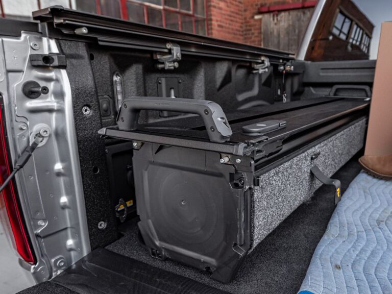 RealTruck RetraxPRO EZ-OFF retractable tonneau cover being lifted out of a silver Ford F-150 bed by two people, showcasing the easy removal system in a real-world setting