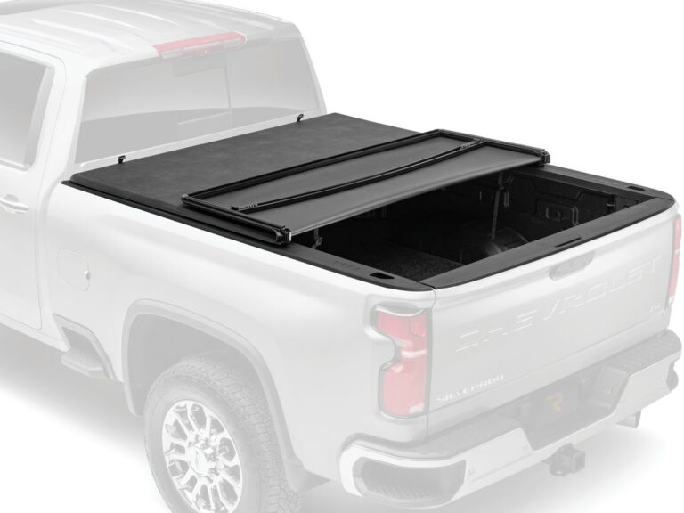 Silver Chevrolet Silverado with the Trifecta E-Series cover partially open, ghosted/dimmed background hero marketing image for the RealTruck product page.