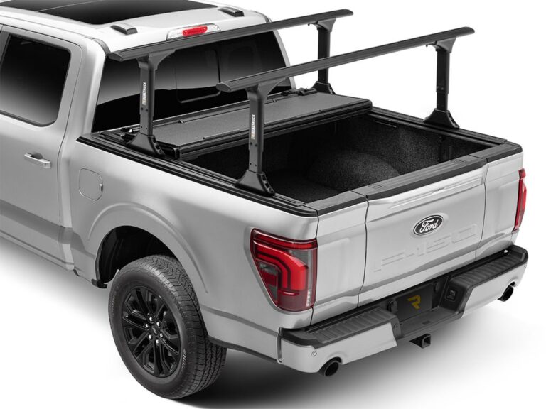 BAKFlip MX4 TS cover fully open and folded forward against the cab on a silver Ford F-150, crossbars remain mounted on the T-slot rails, full bed access view, rear three-quarter angle on white background