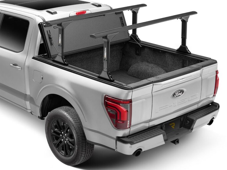 BAKFlip MX4 TS on a silver Ford F-150 with the rear panel flipped up and crossbars mounted, bed partially exposed, rear three-quarter angle on white background