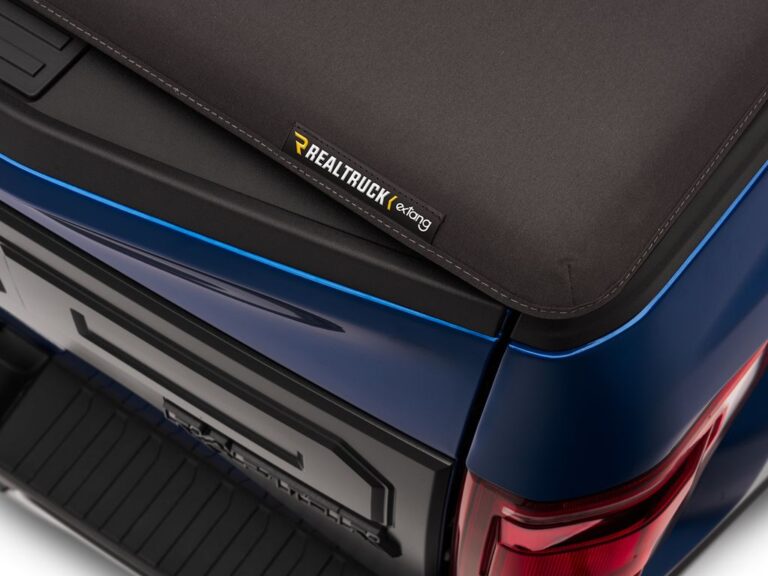 RealTruck x Extang stitched leather-grain canvas badge close-up on the corner of the Trifecta Signature 2.0 cover on a blue truck