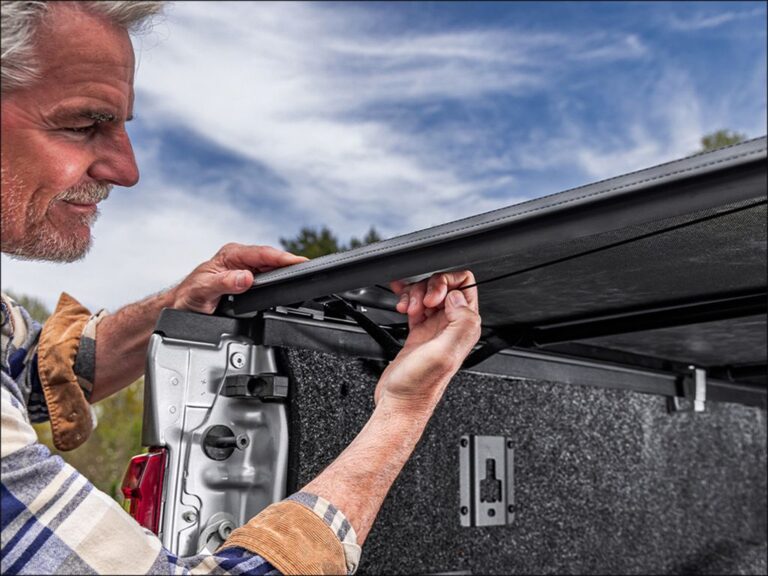 A person installing the TruXedo TruXport GEN 2 cover rail on a truck bed, showing the no-drill clamp system on a cloudy day