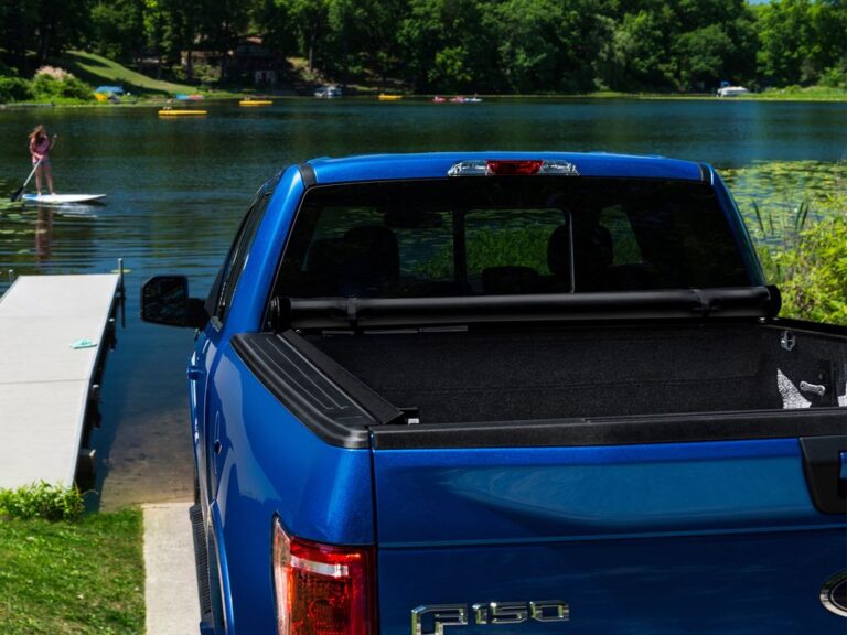 Lifestyle shot of a blue Ford F-150 with the Lo Pro cover installed, parked by a lake with paddleboarders in the background