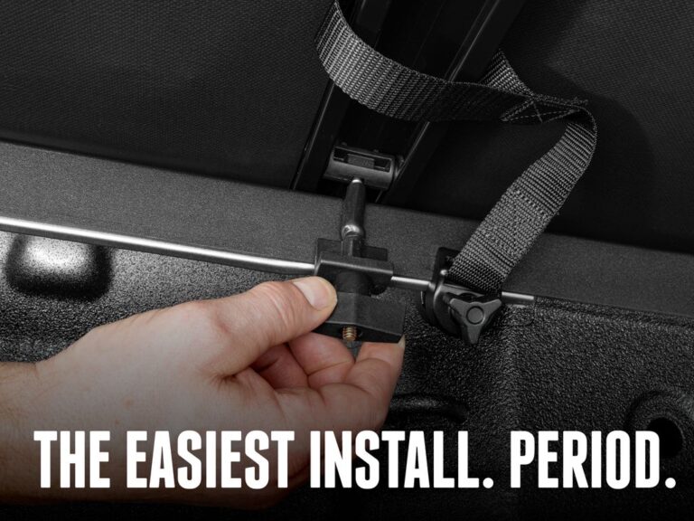 Close-up of a hand securing the integrated buckle strap on the folded Trifecta E-Series cover, text overlay "THE EASIEST INSTALL. PERIOD."