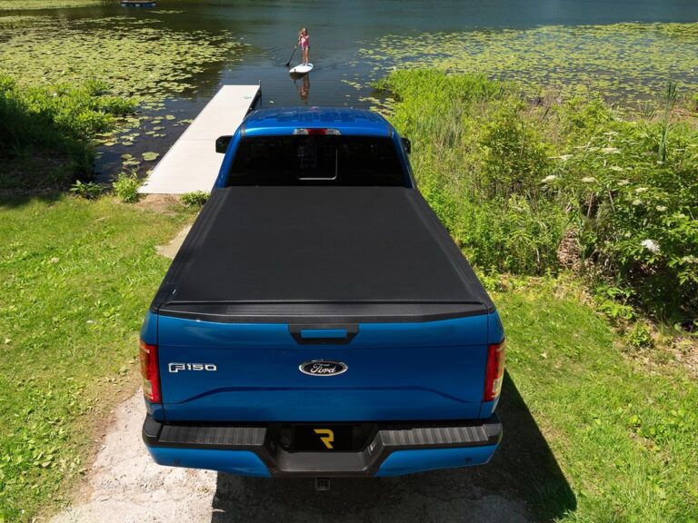 Lifestyle shot of a silver Ford F-150 with the Lo Pro cover partially open in a parking lot