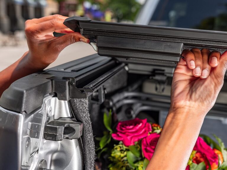 BAKFlip MX4 installation close-up showing hands attaching the side rail to the truck bed