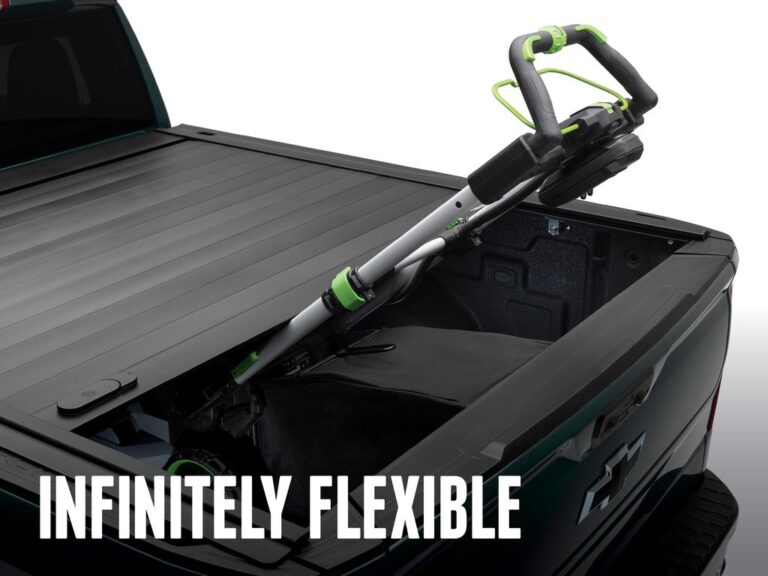 RetraxPRO MX cover partially open on a dark green truck with a lawn mower loaded into the bed, INFINITELY FLEXIBLE marketing overlay showing infinite latch positions