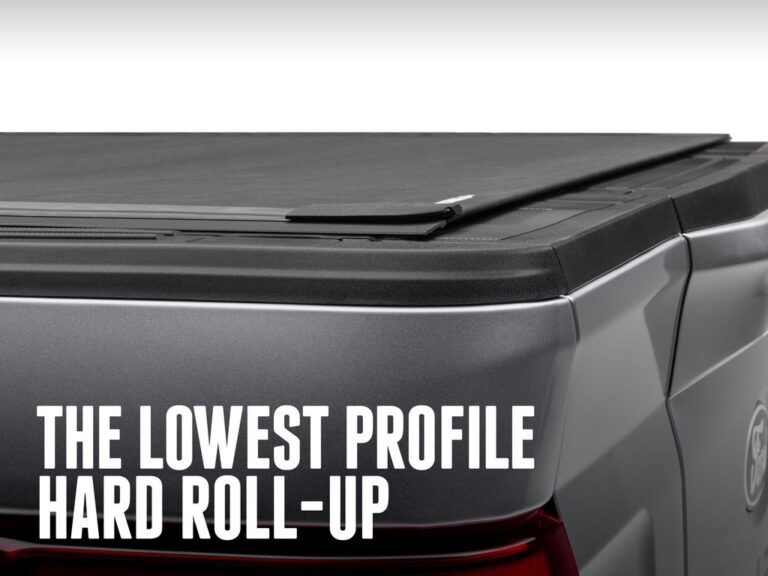 Silver truck low-profile rear three-quarter view of the BAK Revolver X4S hard roll-up sitting flush with the bed rails, with text overlay reading the lowest profile hard roll-up