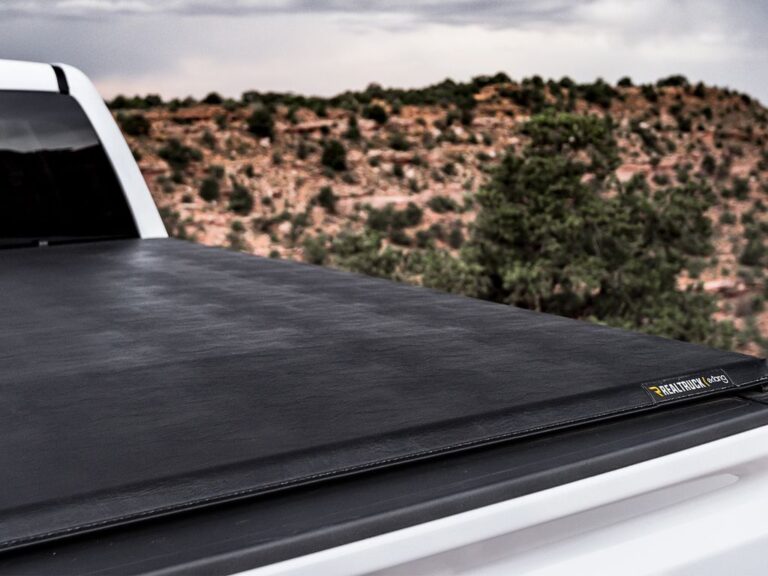 Close-up of the Trifecta 2.0 cover sitting taut on a white truck bed, showing the leather-grain vinyl texture and rear corner seal